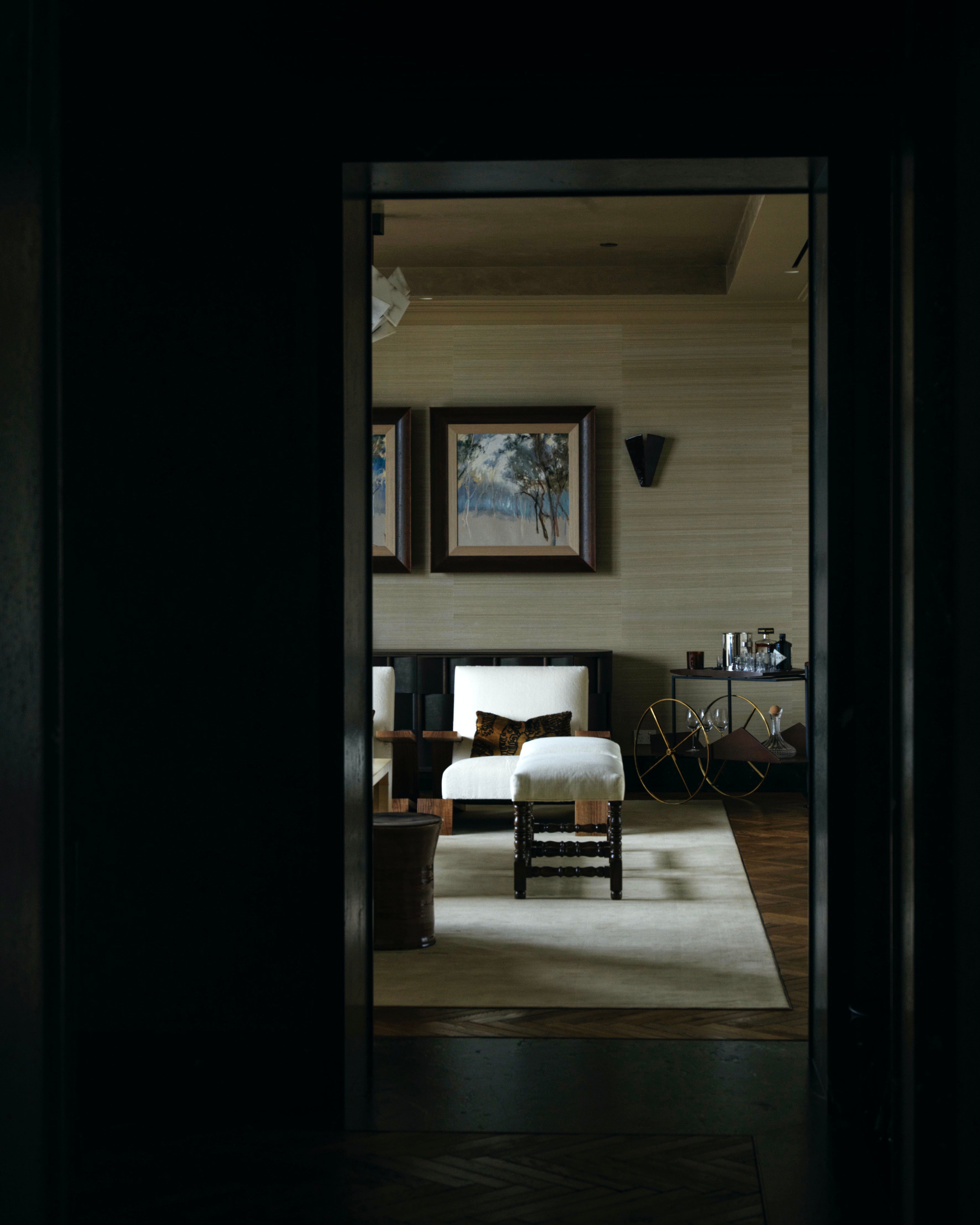 image of a dark hallway with some white chairs and a glazed ceramic stool.