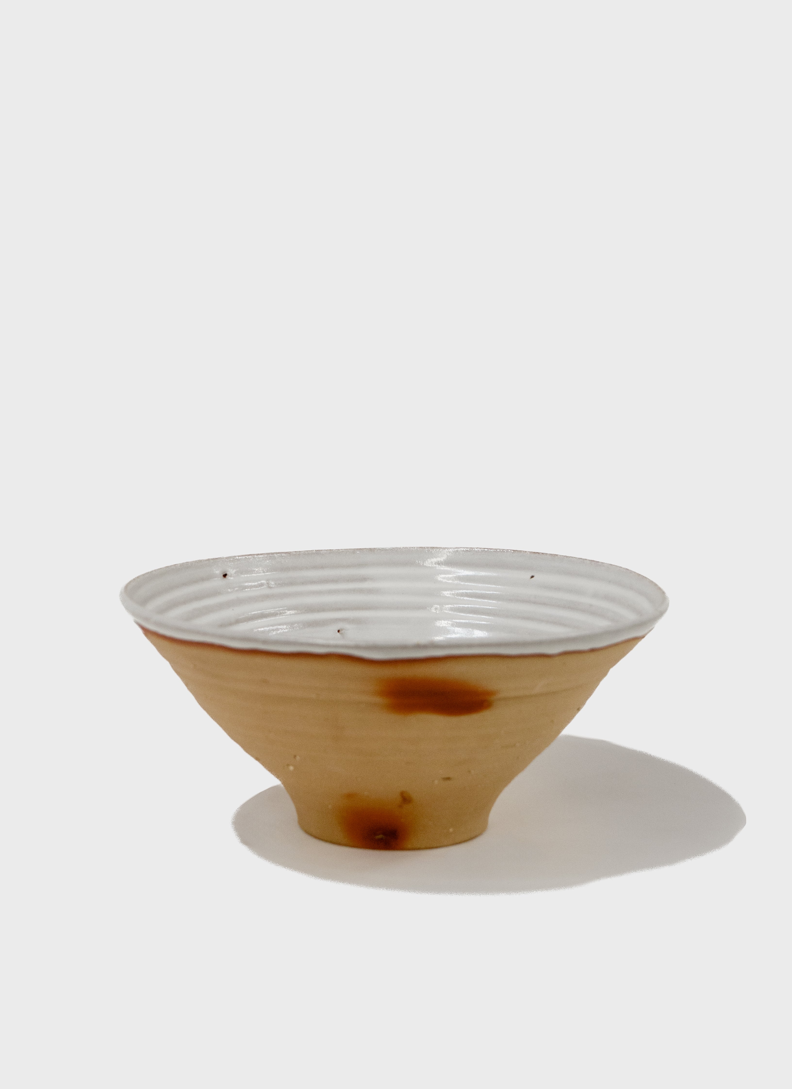 Large ceramic Fruit bowl with Japanese stoneware clay in a toast brown colour and a white matte glaze on the interior. It also features red flashing marks on the exterior. Made in Sydney, Australia by Remy Pajaczkowski-Russell.
