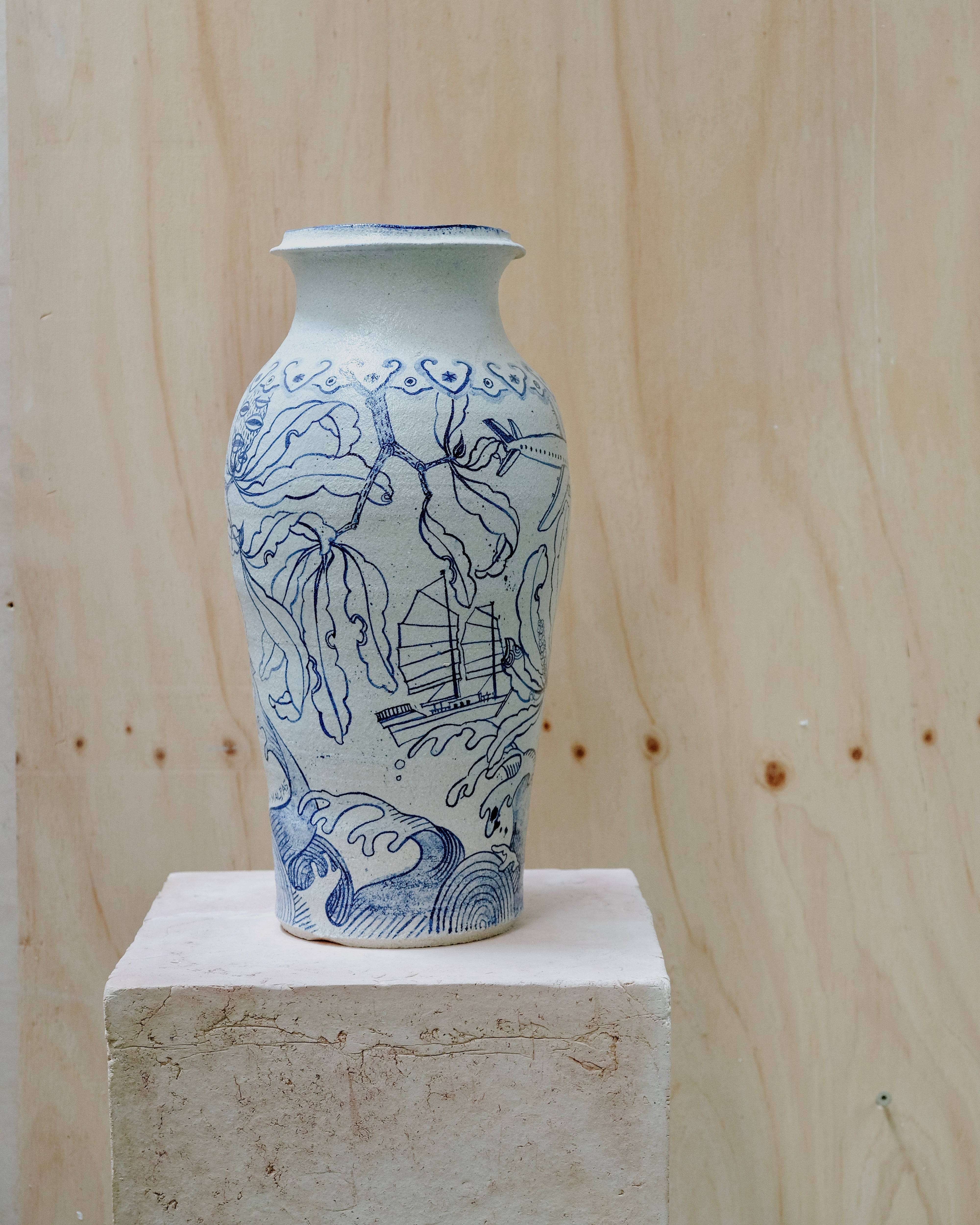 Image of a large white vase with cobalt blue illustration feating branches, waves and a boat.