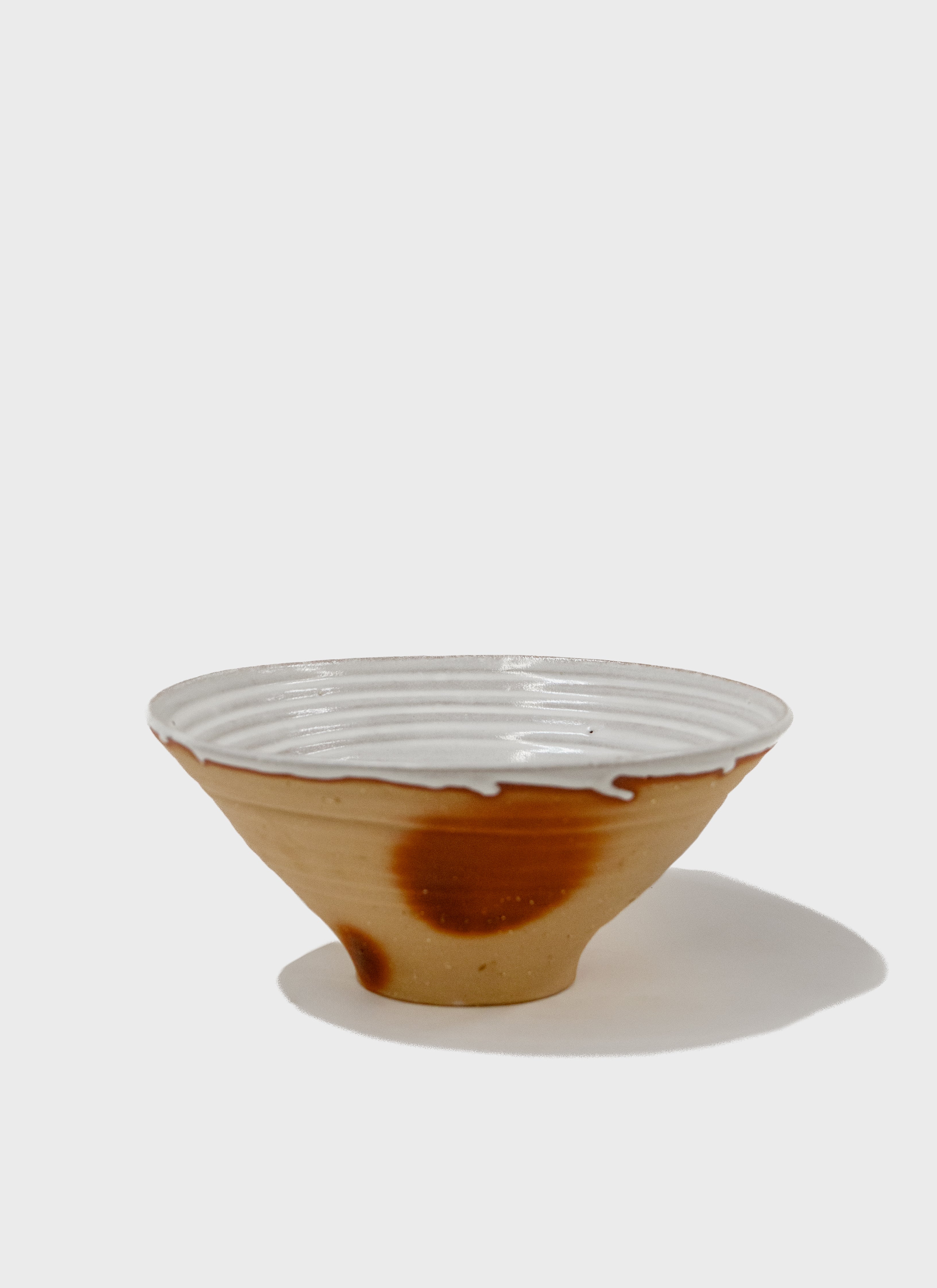 Large ceramic Fruit bowl with Japanese stoneware clay in a toast brown colour  and a white matte glaze on the interior.  It also features red flashing marks on the exterior..  Made in Sydney, Australia by Remy Pajaczkowski-Russell.